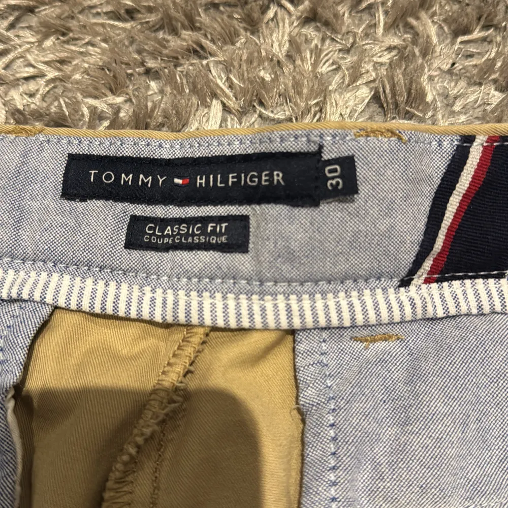 Säljer ett par klassiska beige shorts från Tommy Hilfiger i storlek 30. . Shorts.