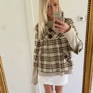 Säljer en superfin rutig kappa i beige och bruna toner. Den har stora knappar framtill och en klassisk krage. Perfekt för höst och vår! Passar till både vardag och fest. 🧥✨