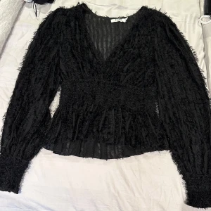Svart blus med textur - Säljer denna svarta blus då den inte kommer till användning. Har använt den få tal gånger och den är i bra skick. 