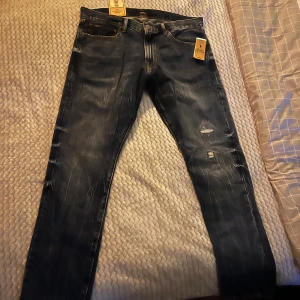 Blå jeans från Polo Ralph Lauren - Säljer ett par snygga blå jeans från Polo Ralph Lauren i modellen Sullivan Slim. De har en cool slitning och dragkedja fram. Perfekta för både vardag och fest! Varing Byxor är väldigt små i storlek. 