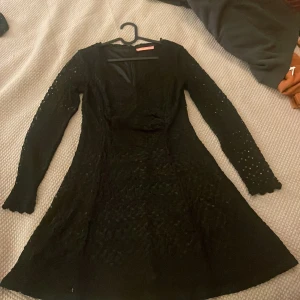 Svart spetsklänning från Pernilla Wahlgren - Säljer en elegant svart spetsklänning från Pernilla Wahlgren. Klänningen har långa ärmar och en v-ringad design. Perfekt för festliga tillfällen med sitt fina spetsmönster och bekväma passform. Den är fodrad för extra komfort. Passar perfekt till höst- och vinterfester!