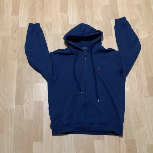 Mörkblå hoodie från Ralph Lauren - Säljer en snygg mörkblå hoodie från Ralph Lauren. Storlek L på den men passar bäst som M/L knappt använd har mest legat i garderoben så därför jag säljer den 