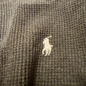 Svart tröja från Ralph Lauren - Säljer en snygg svart tröja från Ralph Lauren i mycket bra skick. Den är långärmad och har en klassisk passform med det ikoniska broderade logotypen på bröstet. Perfekt för både vardag och fest!