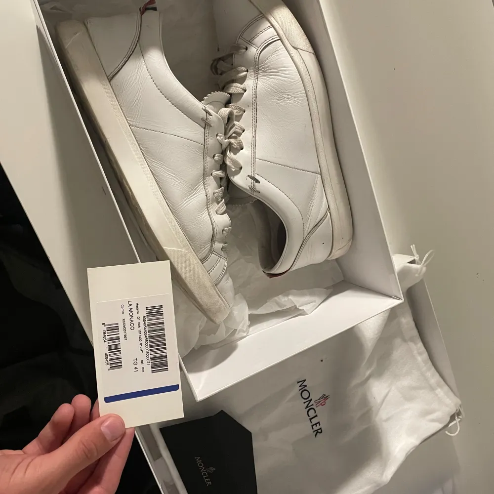 Säljer ett par stilrena vita sneakers från Moncler i skinn. De har klassisk snörning och en bekväm passform. Perfekta för både vardag och festliga tillfällen. Skorna kommer med originalkartong och dustbag. Använda men i bra skick. Storlek 41 men passar 42 och 42,5. Skor.