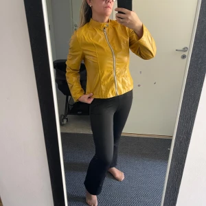 Gul skinnjacka med dragkedja - Säljer en snygg gul falskskinnjacka i mycket bra skick. Jackan har en dragkedja framtill och en stilren design som passar perfekt för vår och höst. Den är långärmad och har en normal passform. Perfekt för att liva upp garderoben med lite färg!Helt ny