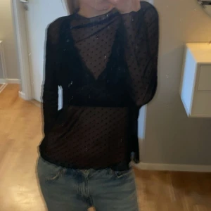 Svart transparent topp från Gina Tricot - Säljer en svart transparent topp från Gina Tricot. Den är långärmad och har ett prickigt mönster. Perfekt för en utekväll eller fest! Toppen är i bra skick och ger en snygg och stilren look.