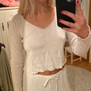 Vit långärmad topp pointelle - Säljer en söt vit långärmad topp med små hålmönster och vågig kant. Perfekt för en avslappnad stil eller som ett basplagg i garderoben. Toppen är i bra skick och har en bekväm passform. STRL S men passar som xs 