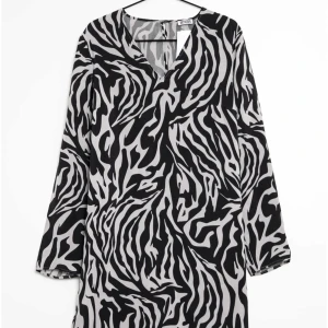 Svartvit zebramönstrad klänning - Säljer en supercool svartvit zebramönstrad klänning med v-ringning. Den har långa ärmar och är perfekt för både vardag och fest. Klänningen är i ett mjukt och bekvämt material som faller snyggt.