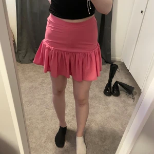 Kjol - Säljer en superfin rosa kjol från Gina Tricot i storlek XS. Kjolen har en volangdetalj och är perfekt för sommaren. Den är i mycket bra skick och har en elastisk midja för en bekväm passform. Perfekt för både vardag och fest! 🌸