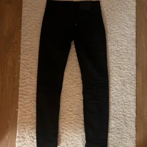 Svarta Levi’s jeans - Säljer ett par svarta Levi’s jeans i väldigt bra skick då de knappt är användna. De har en slim passform och är perfekta för alla årstider. Klassisk design med en knapp och dragkedja framtill. 
