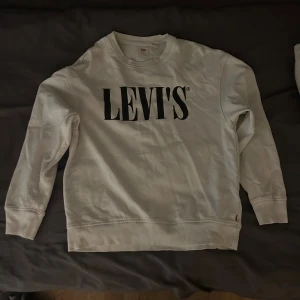 Vit sweatshirt från Levi's - Säljer en knappt använd vit sweatshirt från Levi's i bra skick. Den har en stor logga på framsidan och är perfekt för en avslappnad stil. Tröjan har långa ärmar och en bekväm passform. Perfekt för både vår och höst!