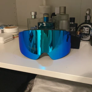 Blå skidglasögon med spegelglas - Säljer ett par coola skidglasögon med blått spegelglas. De har en svart ram och justerbart band för perfekt passform. Perfekta för vinterns äventyr i backen! 🏂