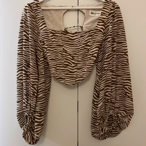 Blus💕💕 - Säljer en supersnygg brun-vit zebramönstrad blus från Kiss the sky. Toppen har en öppen rygg med snörning. Den är som en lite mjukare och skönare korsett vid bröstet, Perfekt för att vara lite mer uppkläd😍🤞 Det står 6 på lappen men ingen storlek, men skulle uppskatta den som xs.