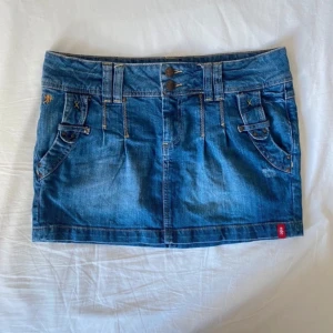 Jeanskjol från edc by Esprit - Supersnygg jeanskjol från Esprit i storlek 38 med snygga detalter! Kjolen är i klassisk blå denim med två knappar fram och coola fickdetaljer både fram och bak. Den är i bra skick men då den inte passade mig så säljer jag den vidare!  😃 Midjemått 42cm, längd 32cm