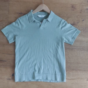 Grön pikétröja från H&M - Säljer en stilren grön pikétröja från H&M. Den har en klassisk krage och korta ärmar, perfekt för en avslappnad men ändå snygg look. Materialet känns mjukt och bekvämt, idealiskt för vår och sommar. Passar bra till nästan allt!