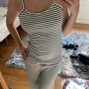 Randig linne i svart och vit - Säljer ett randigt linne i svart och vit med smala axelband. Linnet är figurnära och perfekt för sommardagar. Det har en enkel och stilren design! vintage från Yessica