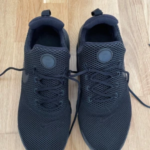 Svarta sneakers från Nike - Säljer ett par svarta sneakers från Nike. Nike Presto i storlek 37.5. De har en stilren design med ett mesh-material som ger bra andningsförmåga. Skorna har snörning och en bekväm sula som passar perfekt för vardagsbruk. Använda fåtal gånger och är i mycket fint skick. 