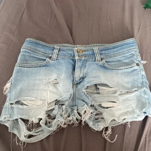Ljusa jeansshorts från H&M Divided - Säljer ett par ljusa jeansshorts från H&M Divided. De är riktigt slitna med stora hål och fransiga kanter för en cool och avslappnad look. Perfekta för sommaren☀️