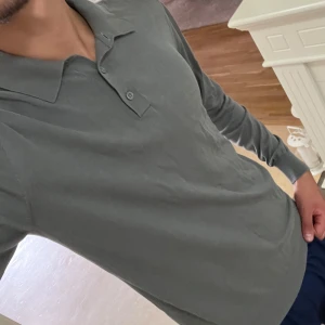 Grå pikétröja från John Henric - Säljer en stilren grå pikétröja från John Henric. Tröjan har en klassisk krage och knappar framtill. Perfekt för både vardag och lite mer uppklädda tillfällen. Skön och bekväm passform!