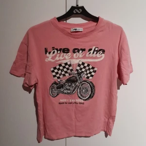 Rosa t-shirt med tryck - En rosa t-shirt med vit och svart tryck.