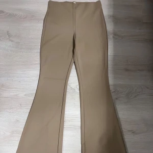 Beige bootcut byxor - Snygga beige bruna  bootcut byxor med hög midja. Byxorna är tillverkade i ett mjukt material som ger en bekväm och snygg passform.