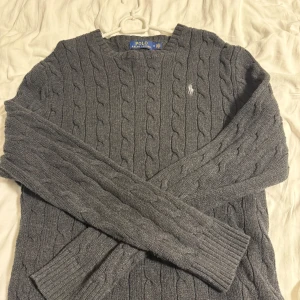 Grå stickad tröja från Polo Ralph Lauren - Säljer denna sjukt snygga Polo stickade tröja. Produkten är i 10/10 skick inga defekter! Tröjan har långa ärmar och en liten broderad logotyp på bröstet. Perfekt för en chill dag med frugan. PRIS KAN DISKUTERAS!!