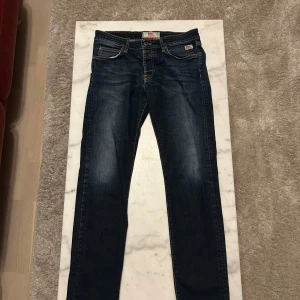 Blå jeans från Roy Rogers - Snygga blå jeans från Roy Rogers med klassisk femficksdesign och diskreta slitningar. Jeansen har en normal passform och är perfekta för en avslappnad stil. Märkeslogga på bakfickan och knappgylf framtill. Original pris ligger på CA 1600kr