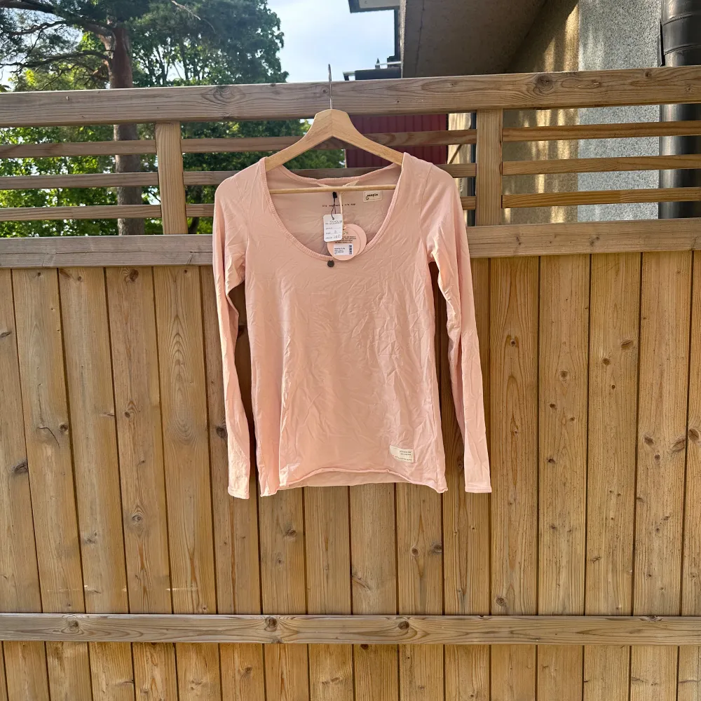 Säljer en ljusrosa långärmad topp. Toppen har en djup v-ringning och en liten knappdetalj framtill. Perfekt för en avslappnad stil. Från märket Odd Molly i storlek 1 som enligt deras storleksguide motsvarar en storlek S. Helt ny med tags. SAMPLE. Yläosat.