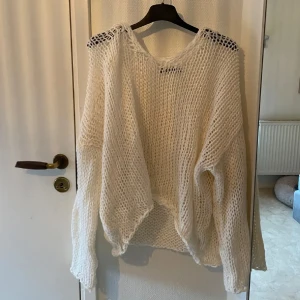 Vit stickad tröja - Säljer en luftig vit stickad tröja med lång ärm och ett grovmaskigt mönster. Perfekt för lager-på-lager-stil eller som en lätt överdragströja. Tröjan har en avslappnad passform och är idealisk för både vår och sommar. Strl L men sitter mer som en oversized tröja om du vanligtvis har s.