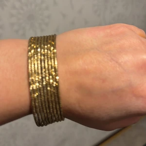 Glittrigt guldarmband - Snyggt glittrigt armband i guldton. Perfekt för att ge en extra touch till din outfit. Armbandet består av flera tunna ringar som ger en elegant och modern look.8st  armband  14k Guldpläterad.