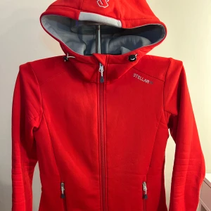 Röd jacka från Stellar Equipment - Snygg röd jacka från Stellar Equipment med huva och dragkedja. Perfekt för kyligare dagar med sin sportiga look och praktiska fickor. Jackan har en modern design och är tillverkad i ett slitstarkt material.