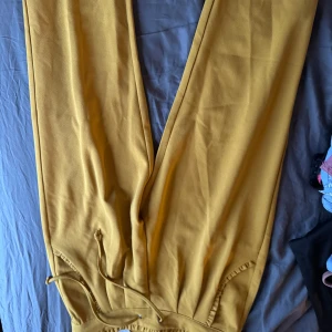 Gula byxor med snörning - Snygga gula byxor med snörning i midjan. Perfekta för en färgglad look. Byxorna har en loose passform och är tillverkade i ett mjukt material som ger en bekväm känsla.