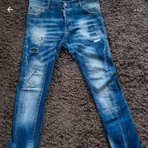 Blå jeans från Dsquared2 - Snygga blå jeans från Dsquared2 med slitna detaljer och en cool tvätt. De har en knappgylf och klassisk femficksdesign. Perfekta för en trendig look.