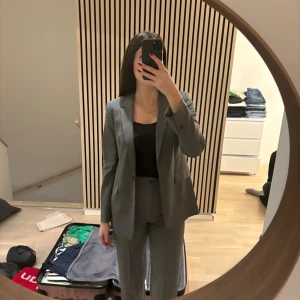 Grå kavaj och byxor - Snygg grå kostym med kavaj och matchande byxor. Kavajen har en klassisk passform med en knapp framtill och byxorna är raka. Perfekt för en stilren look.