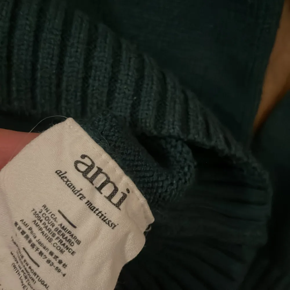 Säljer en snygg mörkgrön stickad tröja från Ami med ett vitt hjärtmönster och bokstaven A på bröstet. Tröjan har långa ärmar och ribbade kanter vid hals, ärmslut och nederkant. Perfekt för kyliga dagar!. Neuletakit & Villapaidat.