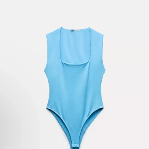 Ljusblå ärmlös bodysuit - Snygg ljusblå bodysuit med ärmlös design och rund hals. Perfekt för att matcha med jeans eller kjol för en stilren look. SLUT I LAGER