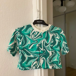 Cool t-shirt Gina Tricot  - Cool tisha från Gina Tricots barnavdelning 💚🩵 Finaste mönstret! Croppad så perfekt till sommaren eller att ha lager på lager 🌿Jättemjuk! Barnstorlek 164, så som en vanlig S-M då den är oversize 🤩Använd men i fint skick! Riktigt snygg till typ fitted jeans! 