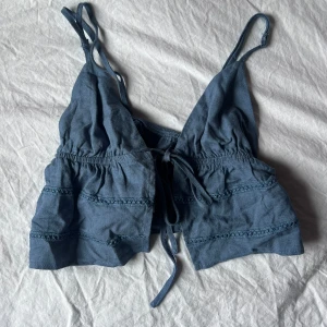 Blått knyt linne - Gulligt blått linne med knyt fram, smala axelband, ganska kort. Passar xs/s. Knappt använd