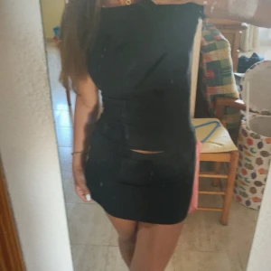 Svart kort kjol och tröja alobha  - Snygg svart kjol och en tajt tröja med öppen rygg med en tight passform. De har en stilren design. Perfekt för en kväll ute eller en speciell tillställning