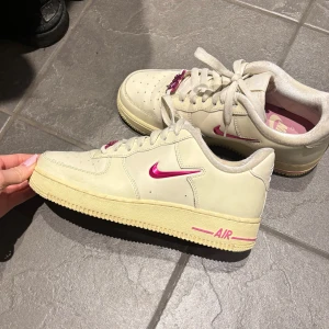 Nike Air Force med rosa detaljer - Snygga Nike Air Force sneakers i en krämvit färg med rosa detaljer. Står JUST DO IT vid snörningen. Sparsamt använda. Nypris 1500kr. 