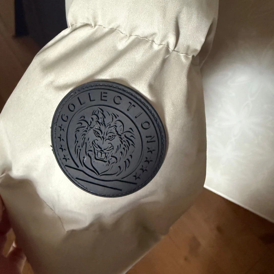 Grå pufferjacka med svart emblem - 1