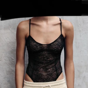 Svart spets body  - Snygg svart spets body  med tunna axelband och ett elegant mönster. Perfekt för en stilfull look. 