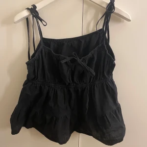 Svart topp💕 - Säljer en svart ärmlös topp med knytband på axlarna och en söt rosett framtill. Köpt från H&M💕