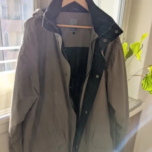 Beige parkajacka från oscar jacobsson  - Säljer en stilren beige parkajacka från oscar jacobsson Jackan har en praktisk dragkedja och knappar framtill samt stora fickor. Perfekt för kyligare dagar med sin långa ärmar och skyddande huva