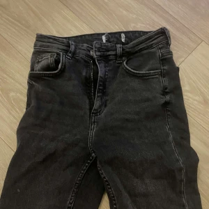 Svarta jeansbyxor - Snygga svarta jeansbyxor med dragkedja och knapp framtill. De har en klassisk femficksdesign och ser ut att ha en tight passform. Perfekta för en stilren look. Har även slits där nere 