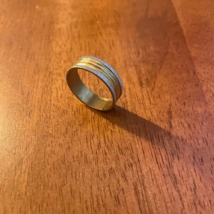 Ring i silver och guld - Elegant ring med en kombination av silver och guld. Designen har flera tunna band som ger en stilren och modern look. Perfekt för att lägga till en touch av elegans till din stil.