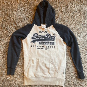 Grå och svart hoodie från SuperDry - Säljer en snygg grå och svart hoodie från SuperDry. Strl l. Bra skick. Skriv vid frågor.