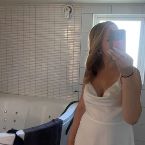 Vit klänning - Säljer en elegant vit klänning med smala axelband och en v-ringad design. Klänningen har en stilren och enkel look, perfekt för sommarens festligheter. Den är tillverkad i ett lätt och bekvämt material som ger en fin passform.