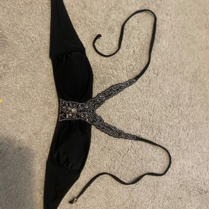Svart bikini med spetsdetaljer - Elegant svart bikini med vackra spetsdetaljer och knytband. Perfekt för en stilfull dag på stranden eller vid poolen.