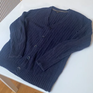 Mörkblå kofta  - Snygg mörkblå kofta från Massimo Dutti i 100% bomull. Den har en v-ringad design med knappar framtill och ribbade muddar. Perfekt för kyligare dagar.